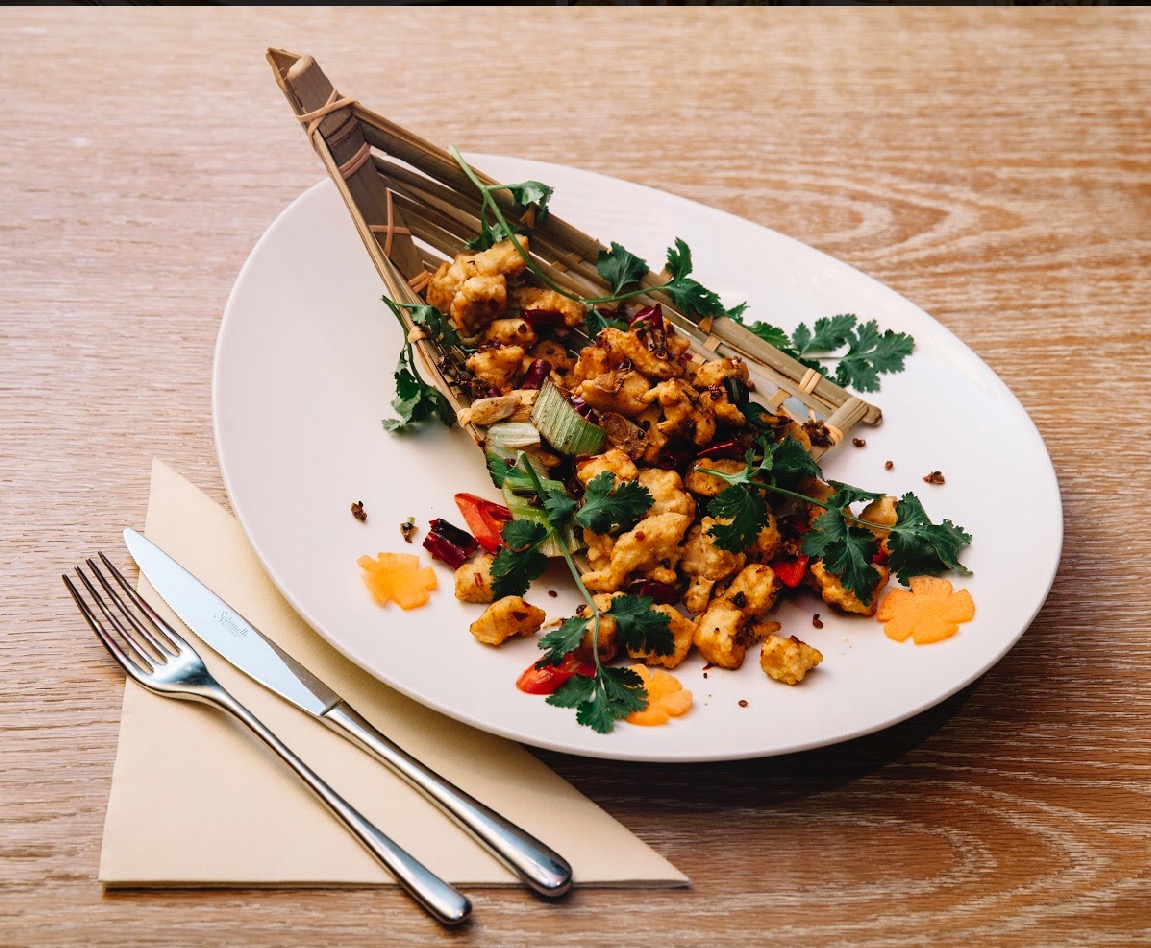 Pollo con profumo piccante alla sichuan servito su canna di bambù