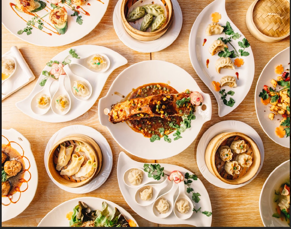 Tavola apparecchiata del Ristorante Stella d'Asia con ravioli, branzino e piatti da condividere